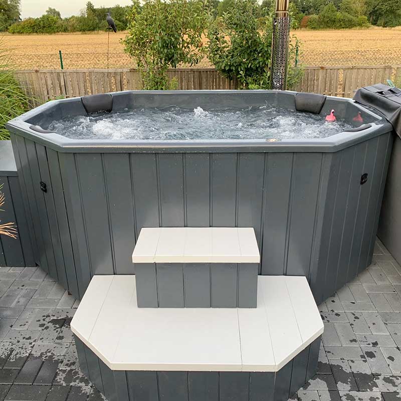 GFK-Zuber, achteckig, 2,4m x 1,8m, Seitenansicht, Grau, im Garten, Wasser befüllt